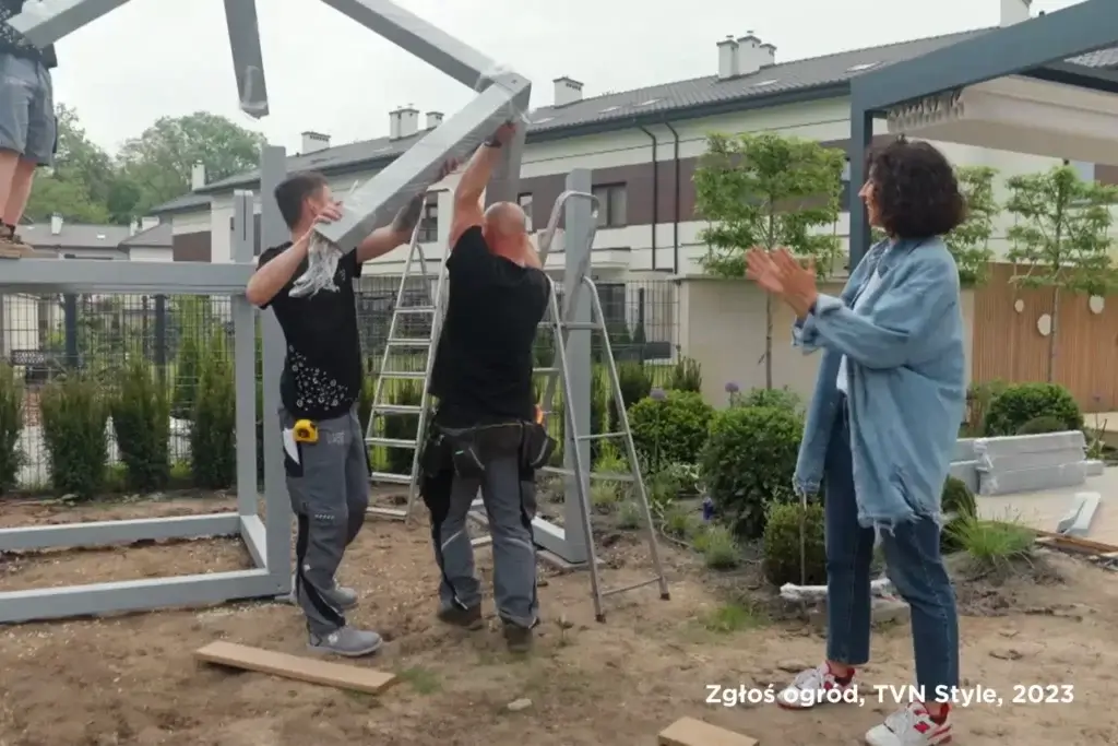 Mężczyźni montują drewniany kącik dla dzieci w ogrodzie od Pinegard w małym ogrodzie.